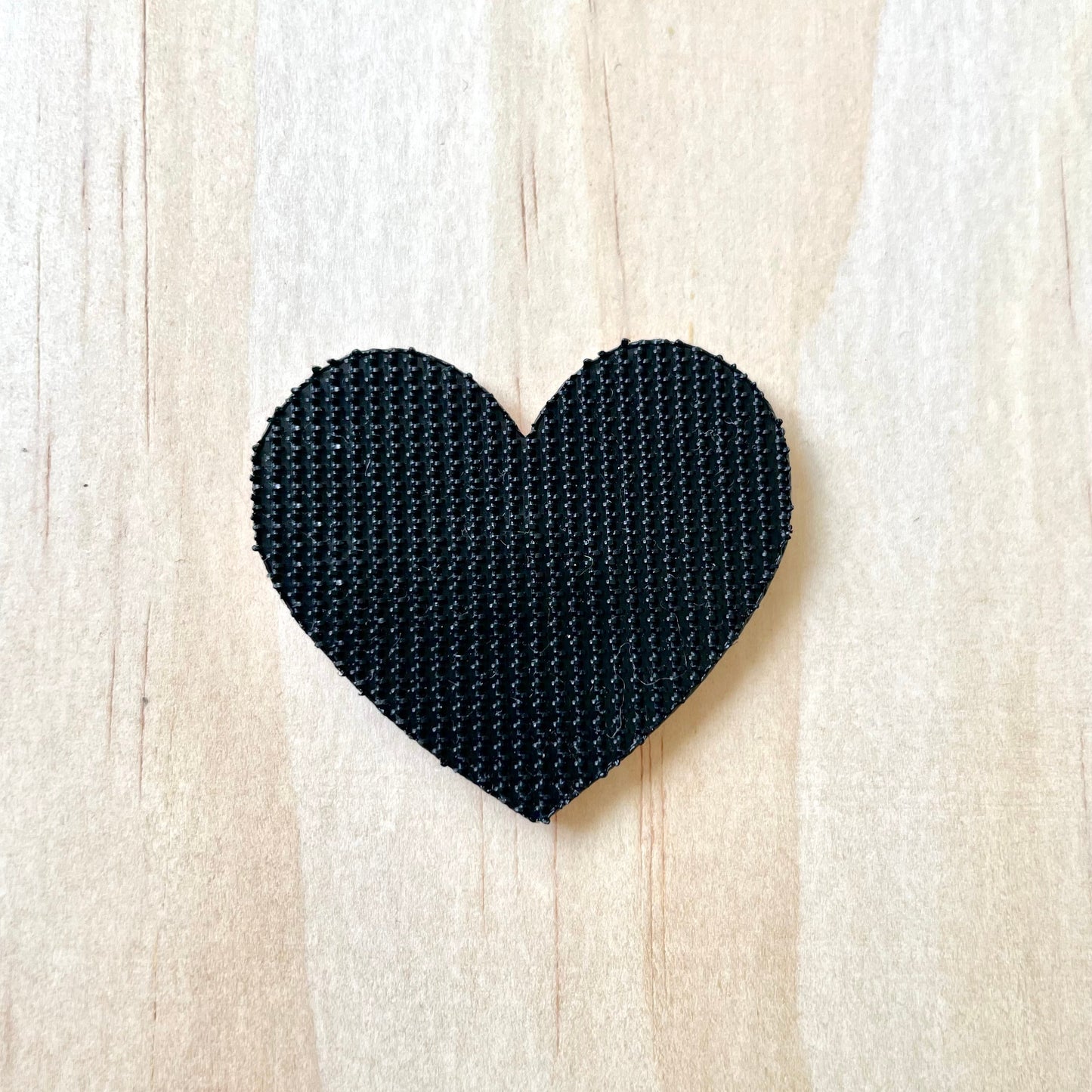 back side of a velcro embroidered patch. heart shaped showing black short hook velcro