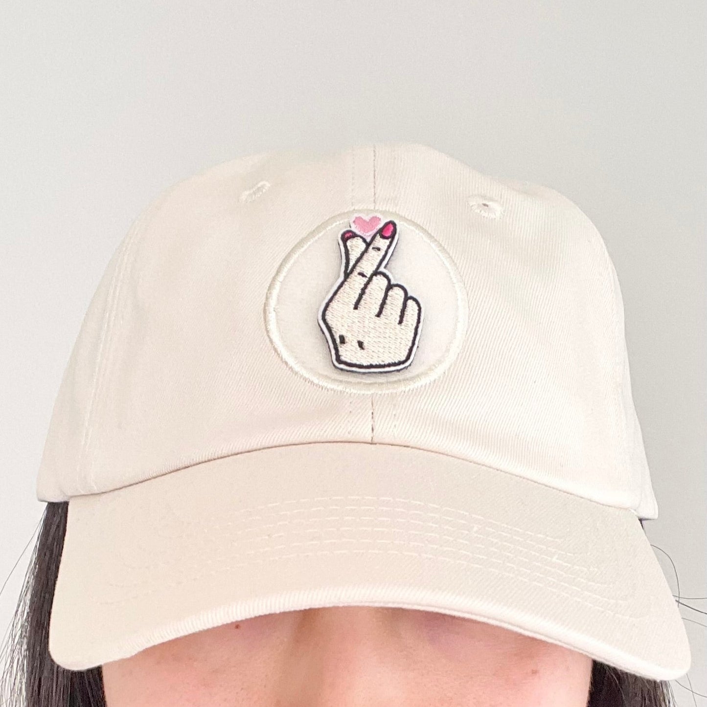 Korean finger heart velcro embroidered patch on cream hat worn by woman model